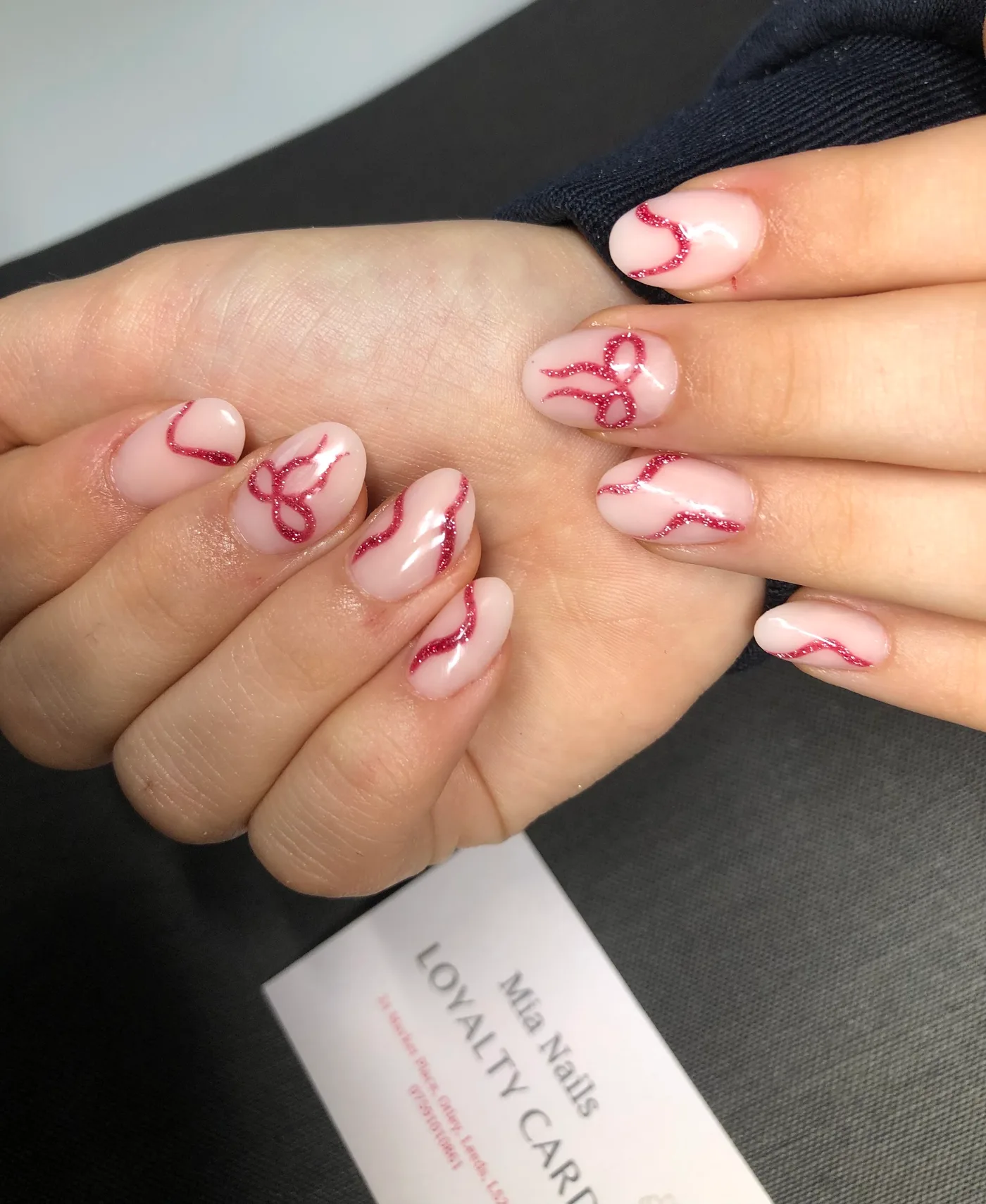 Pink nails with fine red glitter bows and curved details